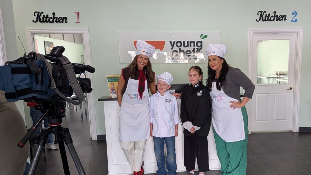5NEWS reporters pose with Young Chefs Academy students during a cooking class at Young Chefs Academy Rogers