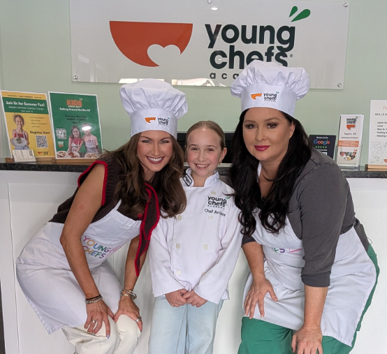 Young Chefs Academy Rogers student poses with 5NEWS reporters during a community cooking class feature