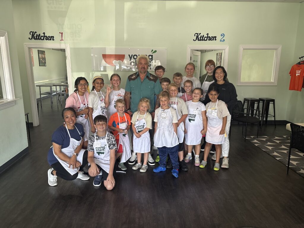 Guy Fieri poses with summer camp students and instructors at Young Chefs Academy Rogers.