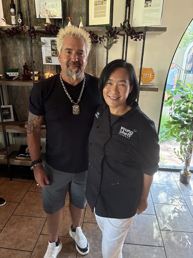 Guy Fieri and Young Chefs Academy Rogers owner Angela pose together during his visit to the Rogers studio.